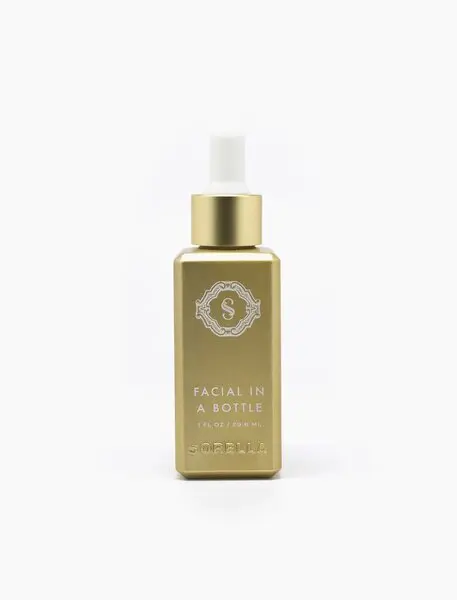 A bottle of facial oil with gold label.