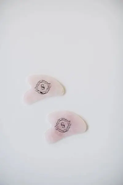 A pair of pink plastic fingertips with the letter s on them.