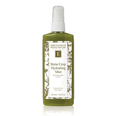 A bottle of facial mist with green leaves.
