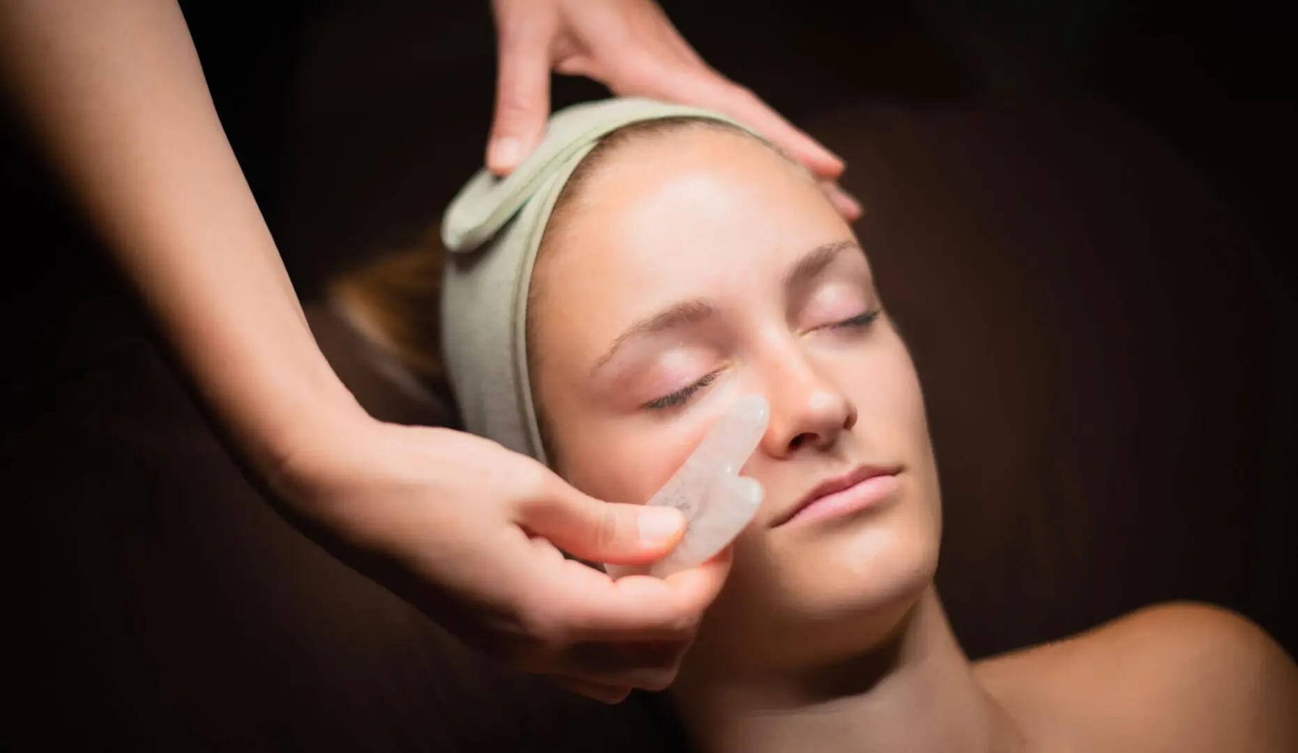 A woman getting her face waxed at the spa.