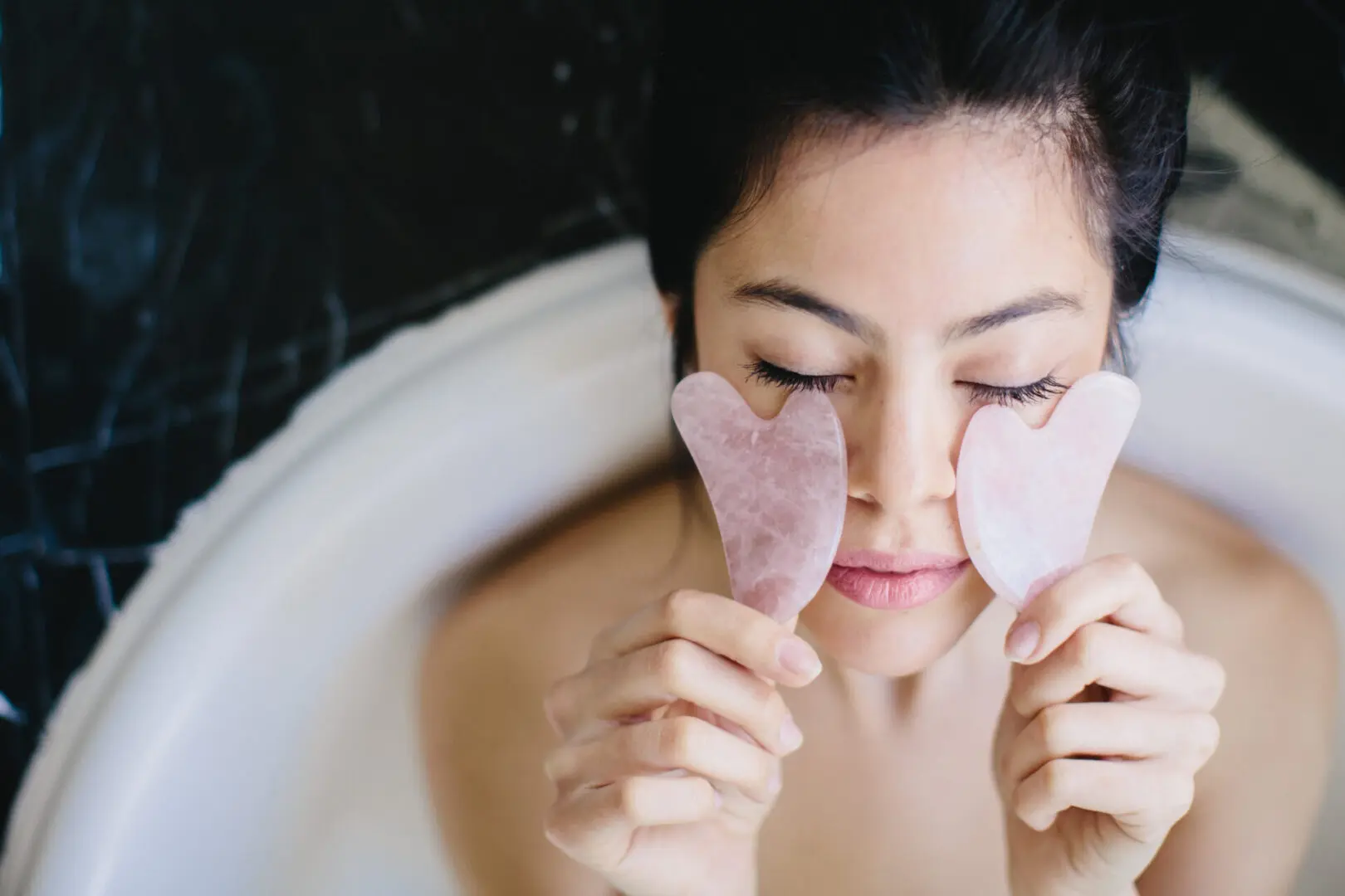 A woman holding two heart shaped soaps in front of her face.