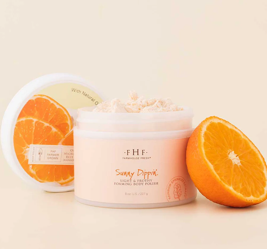A jar of body cream next to two sliced oranges.