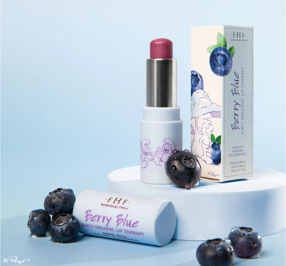 A berry blue lipstick sitting next to some berries.