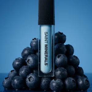 Cosmetic tube with blueberries on blue background.
